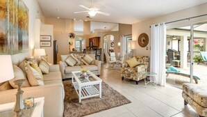 A spacious living area with a sofa, coffee table, and a dining area in the background.