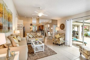 A spacious living area with a sofa, coffee table, and a dining area in the background.