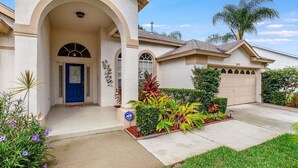A residential house with a covered entrance, a garage, and a well-maintained lawn.