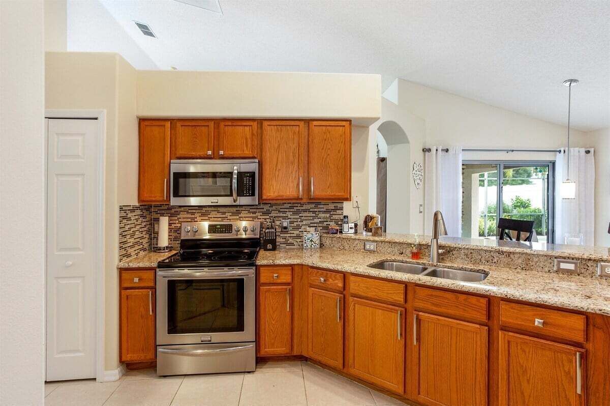 A modern kitchen with wooden cabinets, stainless steel appliances, and a granite countertop.