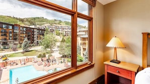 Una camera d'albergo con una grande finestra che si affaccia su una piscina e una zona residenziale.