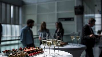 Een tafel met champagneglazen en desserts in een moderne, overdekte omgeving.