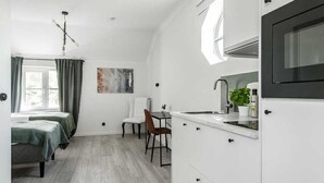 Una cocina moderna con armarios blancos, un horno negro y una ventana sobre el fregadero.