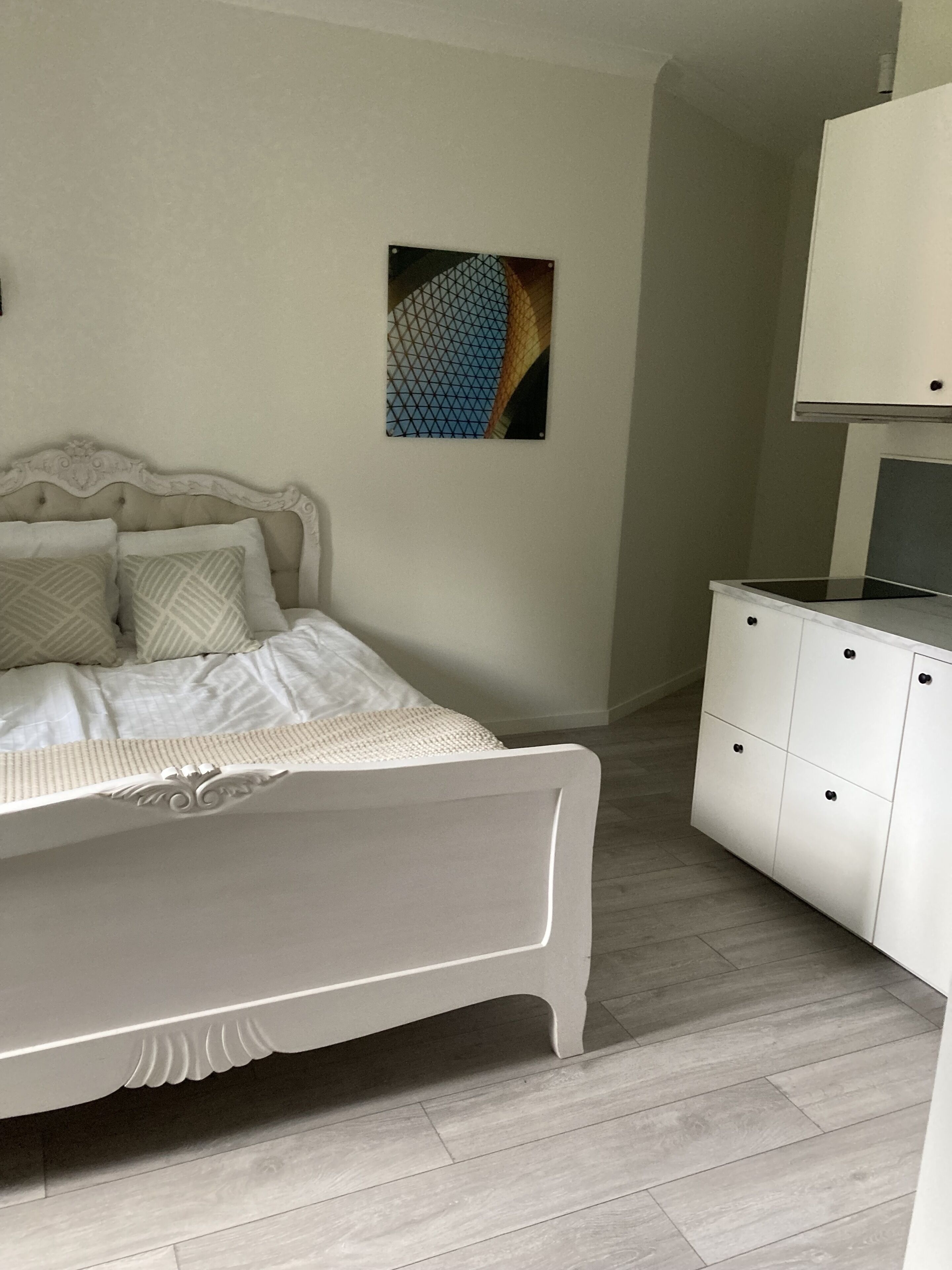 A bedroom with a bed, a dresser, and a wall-mounted artwork.