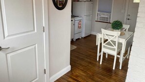 A compact kitchen with white appliances, a dining area with a table and chairs, and a white door.