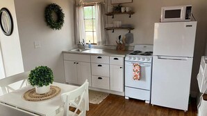 A kitchen with white cabinets, a stove, a refrigerator, and a microwave.