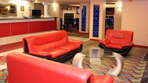Un vestíbulo de hotel con sofás de cuero rojo, una mesa de centro de vidrio y una zona de recepción con una televisión y un letrero que dice "Crystal Star Inn".