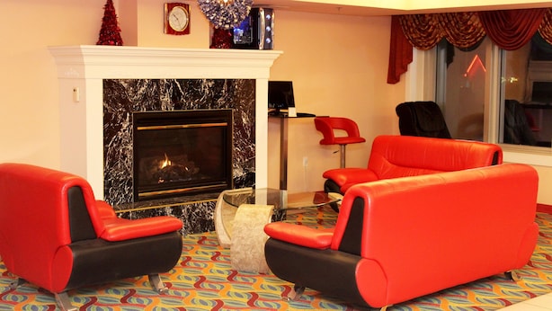 Una sala de estar con chimenea, sofás de cuero rojo, alfombra estampada y un árbol de Navidad.