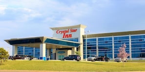 Un hôtel Crystal Star Inn doté d’une façade moderne en verre et d’une enseigne bien visible.