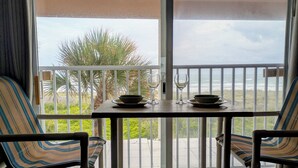 A balcony with a table set for two, chairs, and a view of the ocean. - SUBTROPICAL PARADISE DIRECT OCEANFRONT 2/2 CONDO: STUNNING VIEWS,  HEATED POOL (Cocoa Beach)