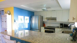 A kitchen with white cabinets, a stainless steel refrigerator, a microwave, and a sink. - SUBTROPICAL PARADISE DIRECT OCEANFRONT 2/2 CONDO: STUNNING VIEWS,  HEATED POOL (Cocoa Beach)