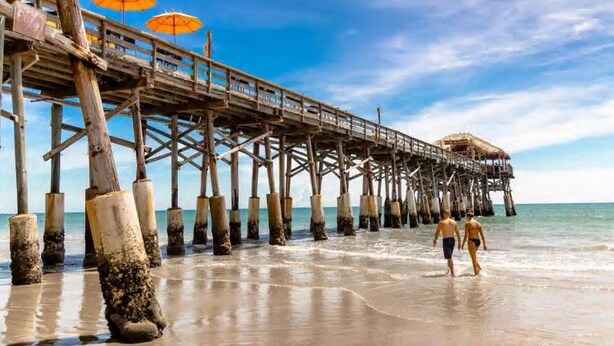 A wooden pier extending into the sea with two orange umbrellas at the end. - SUBTROPICAL PARADISE DIRECT OCEANFRONT 2/2 CONDO: STUNNING VIEWS,  HEATED POOL (Cocoa Beach)