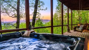 Un jacuzzi con cubierta de madera y vistas a un bosque y montañas.