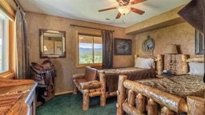 A rustic room with a wooden bed, a wooden desk, and a chair. There is a window with a view of the mountains. - Amazing Views of Shadow Mnt/lake,firepit,3br/2ba Cozy Cabin in Grand Lk,sleeps6 (Grand Lake)