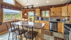 A kitchen with a large island, wooden cabinets, and a view of the outdoors. - Amazing Views of Shadow Mnt/lake,firepit,3br/2ba Cozy Cabin in Grand Lk,sleeps6 (Grand Lake)