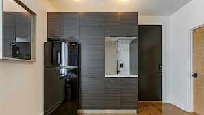 Una cocina moderna con armarios de madera oscura, un refrigerador de acero inoxidable y un enfriador de vinos empotrado.