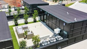 Terraza en la azotea con plantas en macetas, zonas de estar y una estructura de edificio moderna.