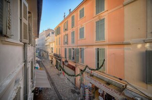 A narrow street with buildings on either side, some with shutters and a shop at the end.