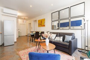 Uma sala de estar moderna com sofá, mesa de centro e área de jantar com cadeiras e mesa.