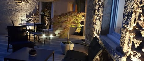 Un patio al aire libre con paredes de piedra, una mesa, sillas y una planta en maceta.