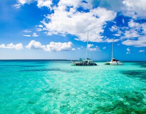 Two sailboats on turquoise water under a clear blue sky.