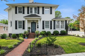 A two-story house with a front porch, a brick pathway leading to the entrance, and a well-maintained lawn. - Elegant Colonial, Heart of Downtown (Greenville)