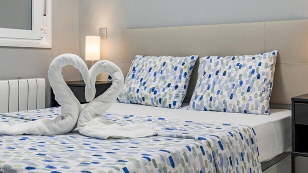 Een hotelkamer met een bed, twee kussens, een bedlampje en een radiator.