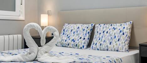 Una habitación de hotel con cama, dos almohadas, lámpara de noche y radiador.