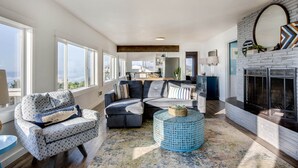 A spacious living room with a fireplace, a sofa set, and a view of the city. - Ocean Front with Spectacular Views! 2 Bedroom, 2 Bath! Seal Rock! (Seal Rock)