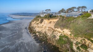 A coastal property with a cliff overlooking the beach, featuring multiple houses and a clear view of the ocean. - Ocean Front with Spectacular Views! 2 Bedroom, 2 Bath! Seal Rock! (Seal Rock)