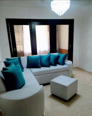 Relax in this stylish living room with a comfortable sofa, ottoman, and chandelier.