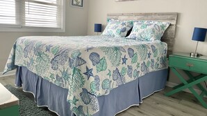A bedroom with a bed, a nightstand, a lamp, a window with blinds, and a painting on the wall.