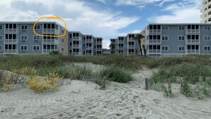 A beachfront hotel with multiple-story buildings, a sandy path leading to the entrance, and a clear sky. - Direct Oceanfront Corner Unit Villa, 2BR 2Bath, large pool, million dollar view! (North Myrtle Beach)