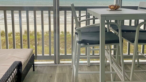 A balcony with a view of the ocean, a table with chairs, and a wicker sofa. - Direct Oceanfront Corner Unit Villa, 2BR 2Bath, large pool, million dollar view! (North Myrtle Beach)