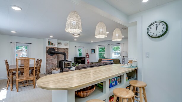 Una cocina moderna con una isla central, iluminación colgante y un reloj en la pared.