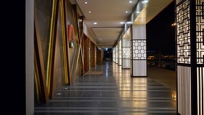 A corridor with modern lighting, reflective flooring, and decorative panels. - Cama Hotel (Mohali)