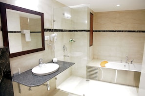 A modern bathroom with a sink, mirror, and shower area. - Hotel Cama (Mohali)