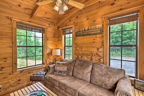 A wooden cabin interior with a leather sofa, a table with a candle, and a sign on the wall. - Quaint Log Cabin w/ Views Near West Jefferson (Warrensville)