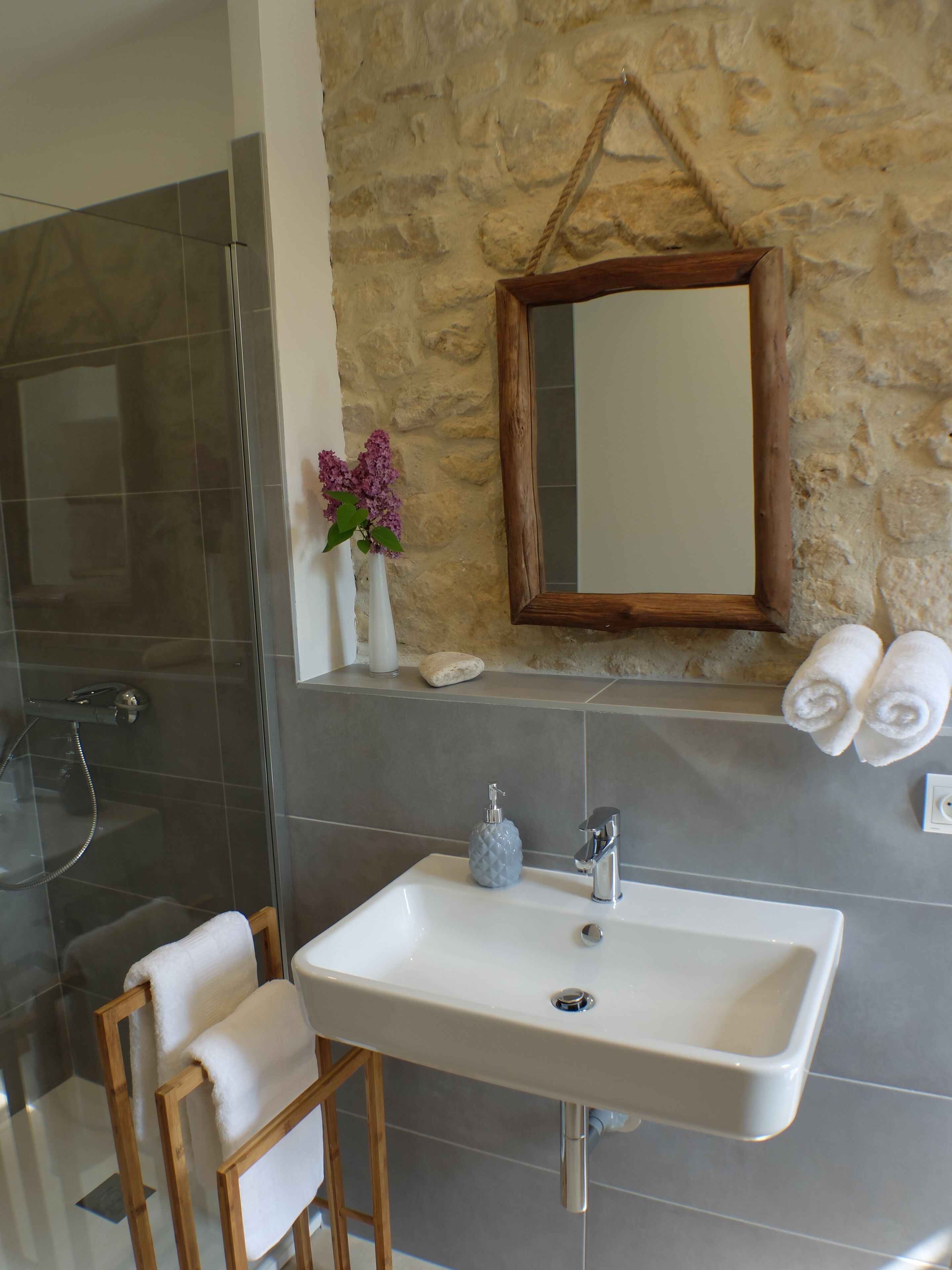 A bathroom with a shower, a sink, a mirror, and towels.
