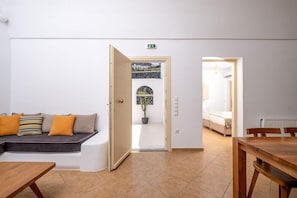 A modern interior with a sofa, a dining table, and a view through a door. - Alter Ego Villa (Santorini)