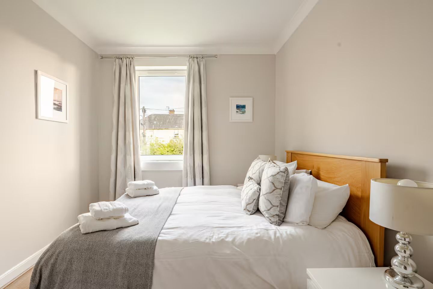 Une chambre d’hôtel avec un lit, une table de chevet, une lampe et une fenêtre avec des rideaux.