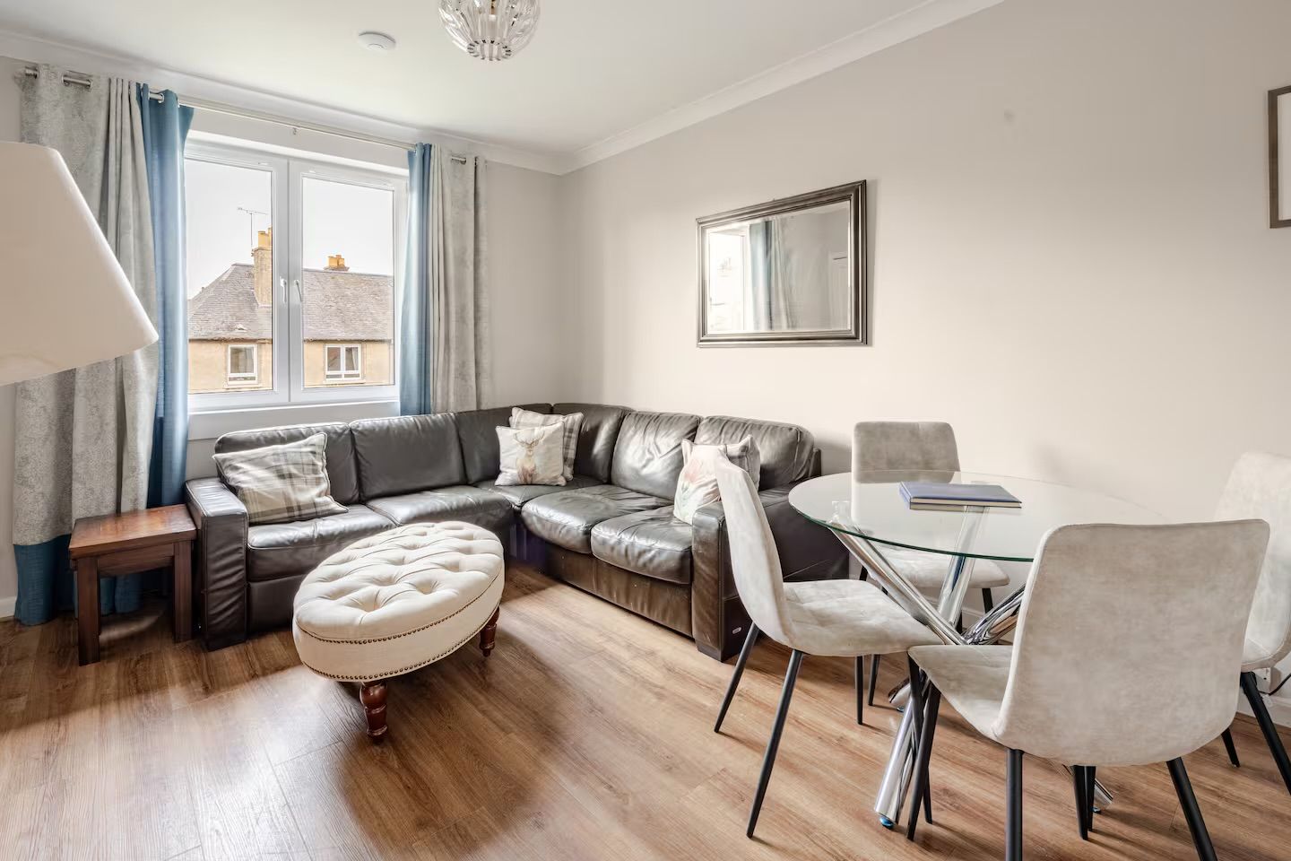 En moderne stue med en lædersofa, et glasbord og et spiseområde med stole.