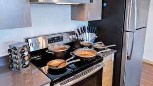 Una cocina moderna con electrodomésticos de acero inoxidable, que incluyen una estufa con ollas, un refrigerador y un bloque para cuchillos.