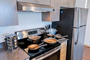 Una cucina moderna con elettrodomestici in acciaio inossidabile, tra cui un piano cottura con pentole, un frigorifero e un coltellinaio.