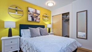A hotel room with a bed, bedside tables, a wardrobe, and a mirror. - Beacon Ave S 1BR - Balcony + City Views - Link Rail - Monthly Stays (Seattle)