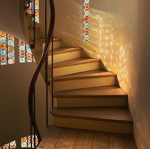 Una escalera de madera con barandilla, que lleva a una plataforma.