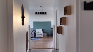 A hallway with wooden flooring, a ceiling with a skylight, and a seating area with a sofa and a coffee table.