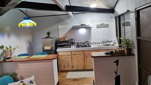 Una cucina compatta con mobili in legno, un piano di lavoro e una lampada a sospensione.