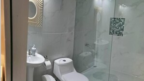 Un bagno moderno con toilette, lavabo e cabina doccia in vetro.