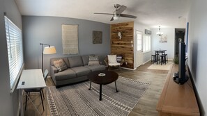 A living room with a grey sofa, a coffee table, a floor lamp, and a patterned rug.